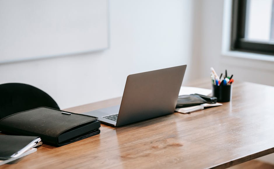 A clean workspace featuring a modern laptop on a wooden desk, ideal for productivity