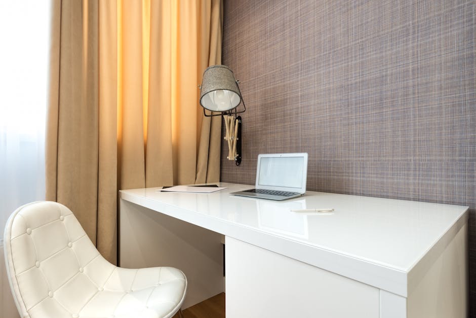 Stylish modern workspace featuring a laptop on a sleek desk with an elegant white chair and ambient lighting